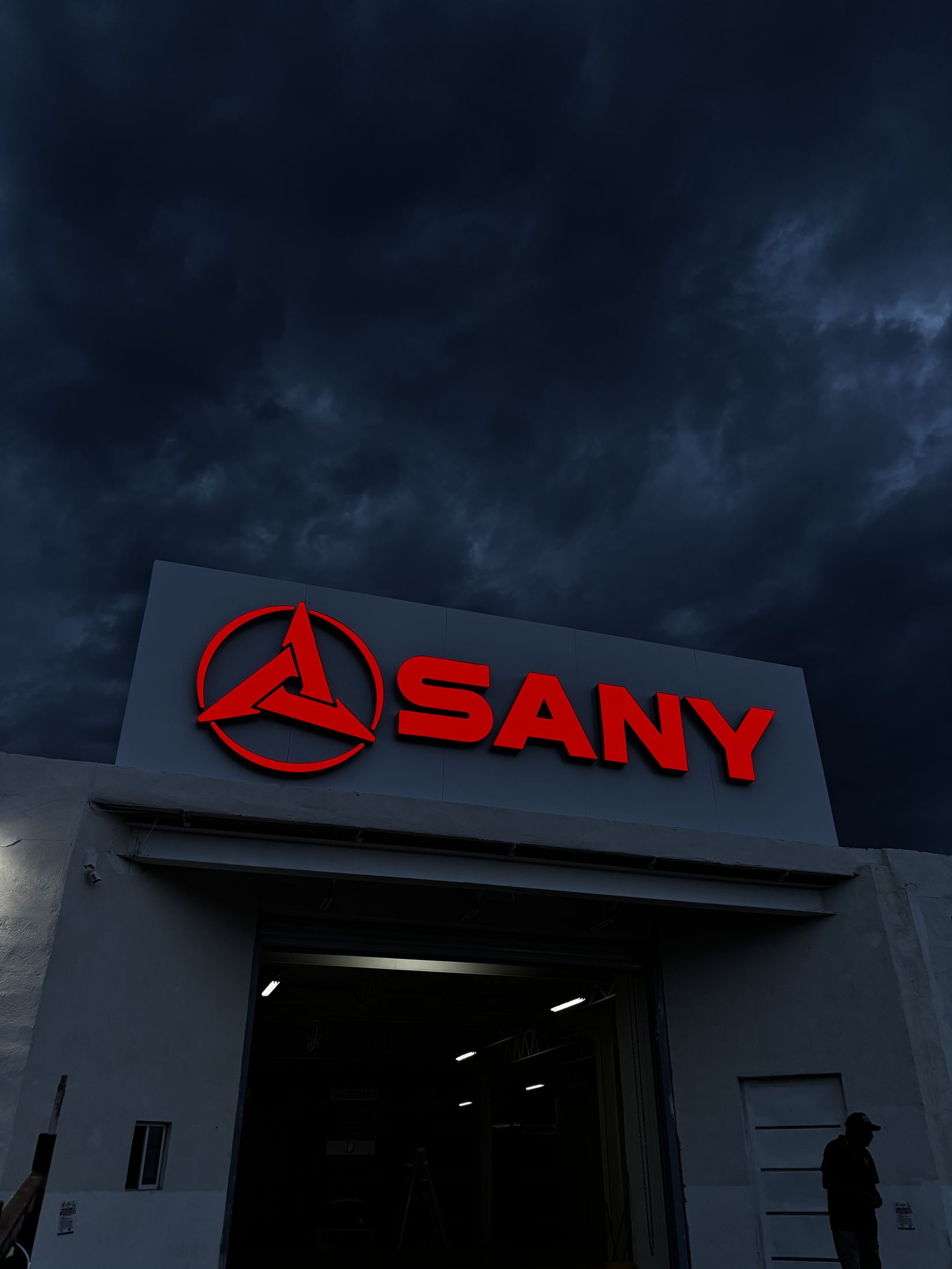 Letras iluminadas SANY instaladas por JR Signs bajo un cielo de tormenta